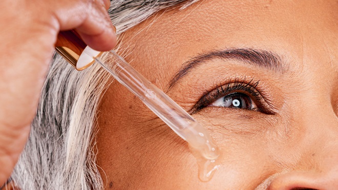 vrouw brengt serum met retinol aan op gezicht