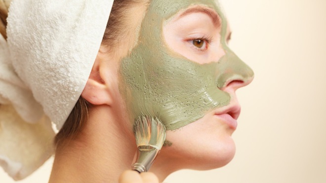 Een vrouw brengt een kleimasker aan op haar gezicht