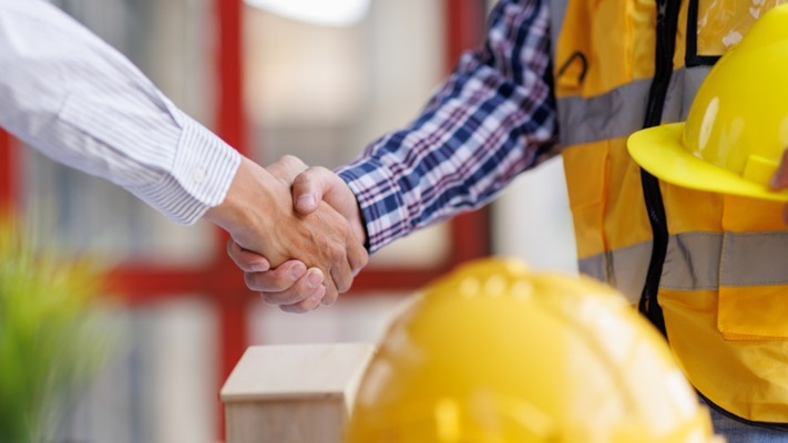 een consument schudt een aannemer de hand