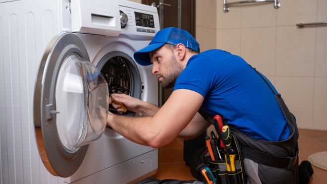 man repareert wasmachine