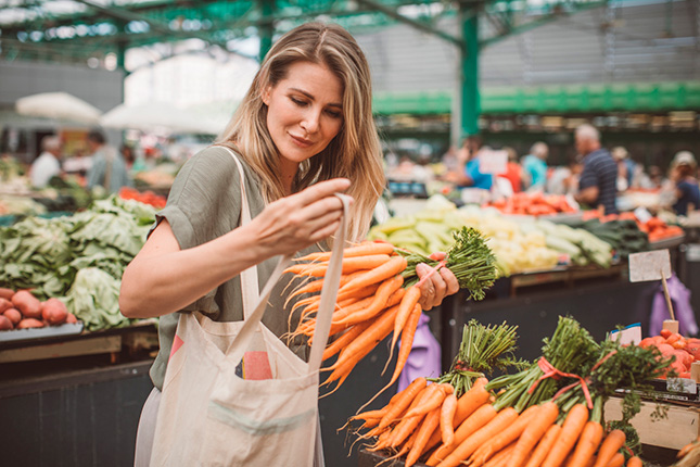 Een vrouw kiest groenten in de supermarkt