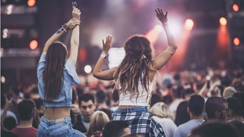 Twee meisjes zitten op de nek van hun vrienden bij een concert op een festival