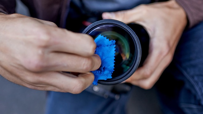 close-up van iemand die de lens van zijn camera aan het reinigen is