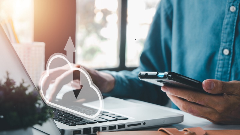 Een man gebruikt cloudopslag tussen zijn computer en zijn telefoon