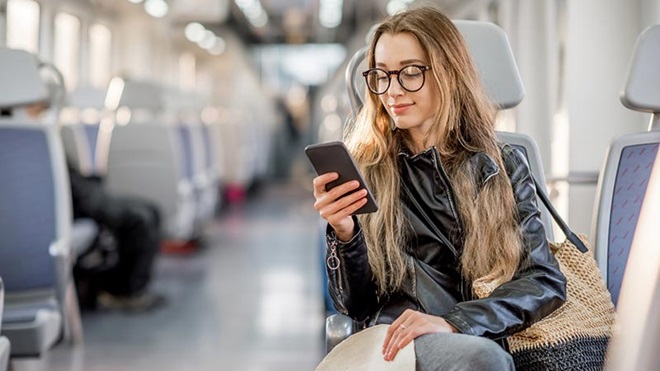 Vrouw zit in de trein en controleert de data op haar gsm