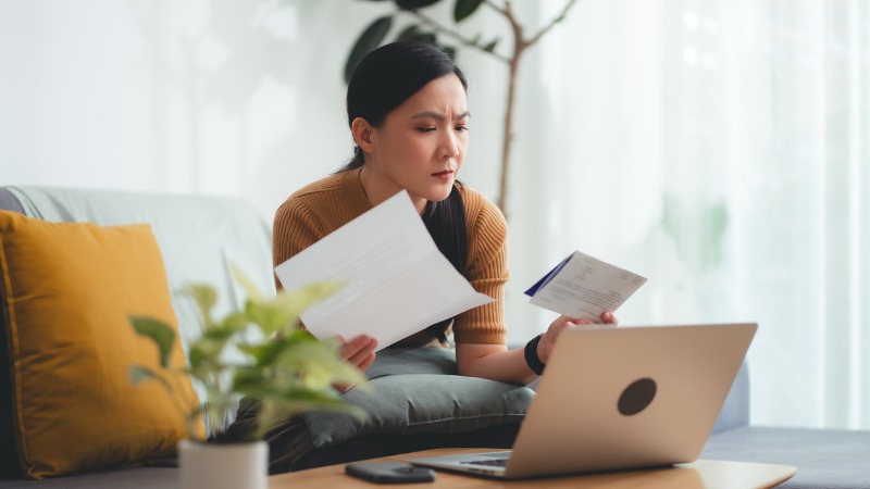 vrouw met rekeningen van telecomoperator achter laptop