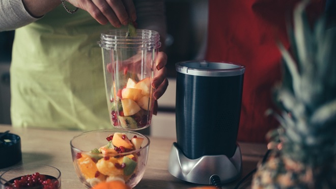 vrouw maakt smoothie met fruit in nutribullet blender