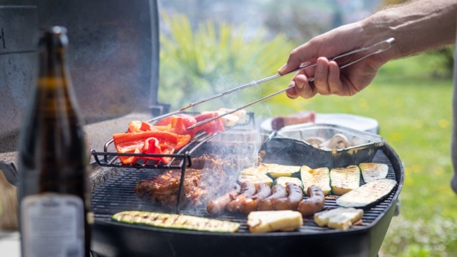 hand grillt groente en vlees op een gasbarbecue