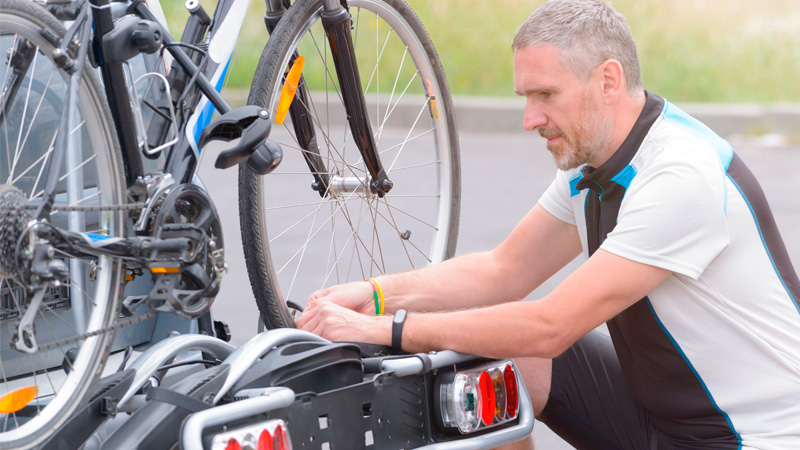 man bevestigt fiets aan fietsendrager