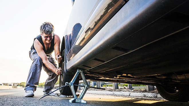 iemand vervangt een lekke band met een krik