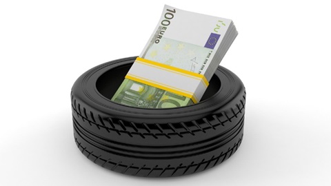 prijs autobanden: stapeltje geldbiljetten van 100 euro liggen in een autoband