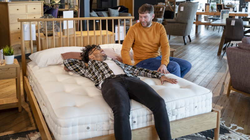  Twee mannen testen een matras in een winkel.