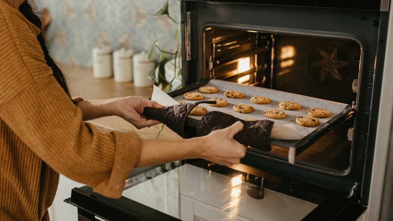 Een reeks koekjes wordt in een oven gestoken.