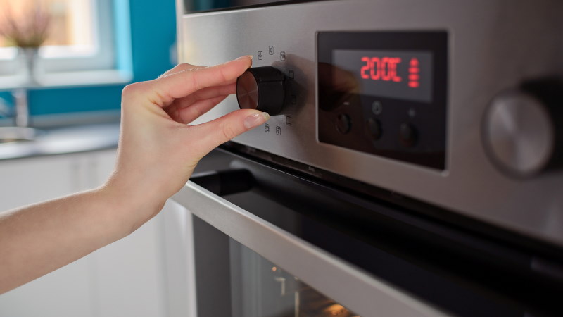 Iemand zet de temperatuur in zijn oven op ongeveer 200°C.