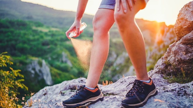 Vrouw gebruikt spray tegen muggen op haar been